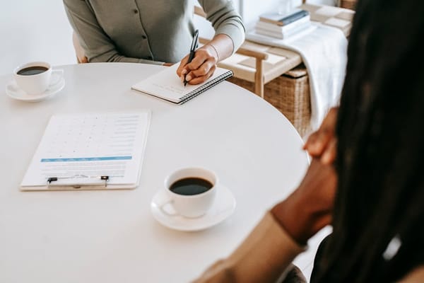 Two individuals having a meeting at a round table with documents and coffee cups