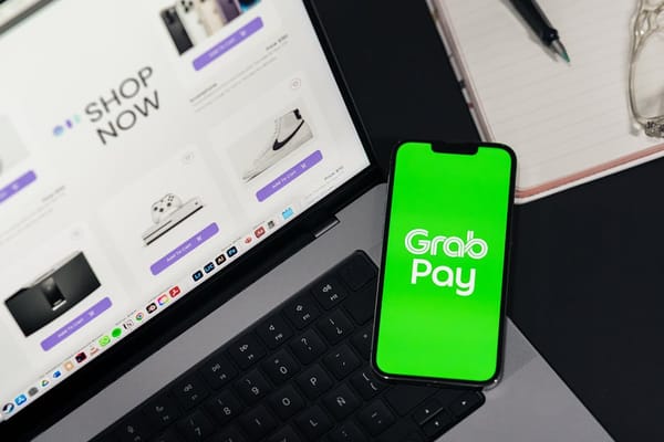 Image showing a laptop with an online shopping website displayed, alongside a smartphone displaying the GrabPay app