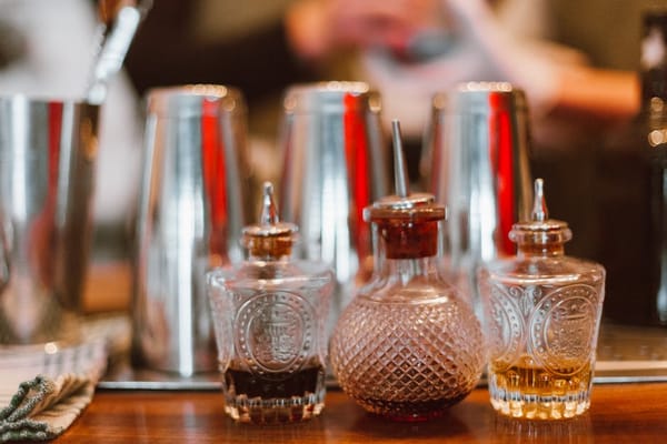 The image shows a close-up view of a bar setting with three ornate glass bottles placed on a counter