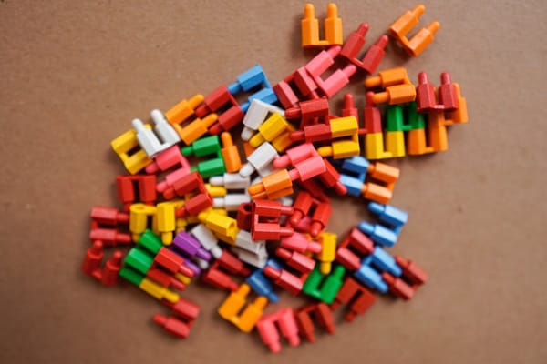 A pile of colorful plastic game pieces on a brown cardboard surface