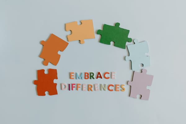 The image features seven colorful puzzle pieces arranged in a semi-circle around the phrase 'EMBRACE DIFFERENCES' in multicolored letters on a light b