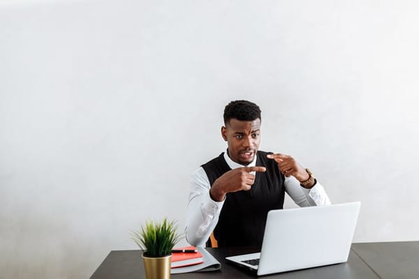 A man sitting at a desk engaged in a video call on his laptop