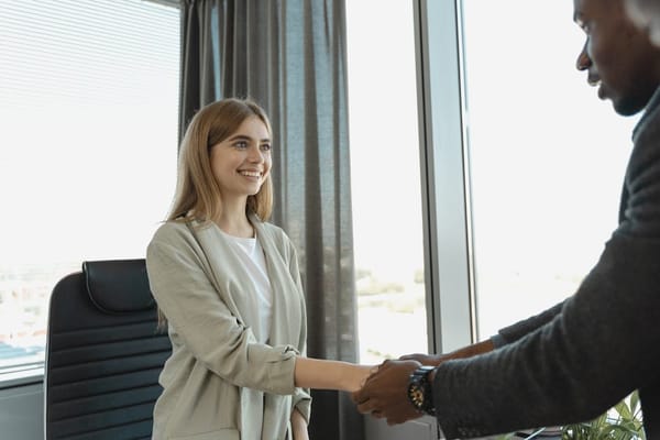 A woman and a man engaged in a handshake in an office setting