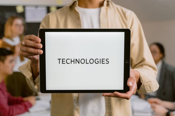 A person is holding a tablet that displays the word 'TECHNOLOGIES' in a bold font